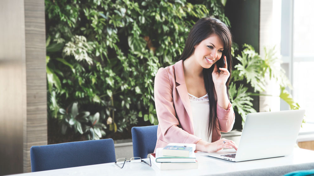 Female virtual receptionist using phone and laptop